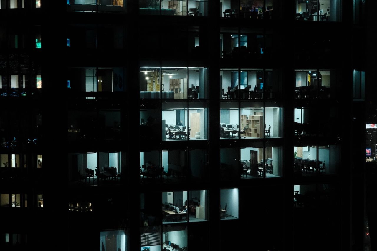 A nighttime view of a modern office building in Warsaw with illuminated interiors.